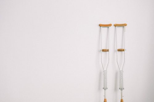 A photo of crutches leaned on a white wall.